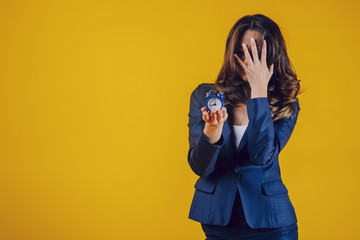 The American woman dressed elegantly as a teacher or business lady, holds a watch in her palm and with her hand in her hair, feels tired and tight and sad.