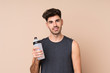 © luismolinero - Young sport man over isolated background with sports water bottle