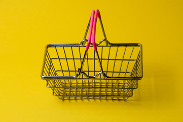 Wall Mural - Shopping basket on a yellow background. Supermarket food price concept.