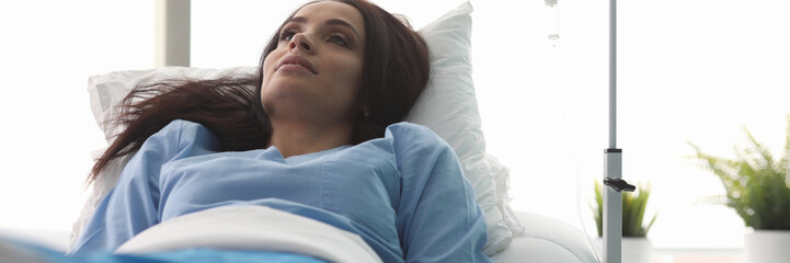 Canvas Print - Portrait of wonderful sick woman lying in hospital ward in clinic. Beautiful businesswoman getting dripping dropper in vain. Healthcare and medicine concept