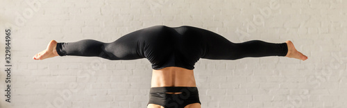Fotografía panoramic shot of girl with barefoot doing wide legged handstand in yoga studio