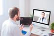 © GENETTICA - Man in front of computer videoconferencing with doctor at home.