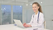 © stockbakers - Cheerful Young Female Doctor Working on Laptop in Office