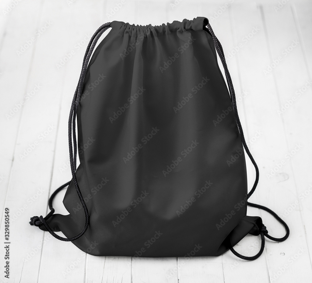 black backpack with strings on planked surface - obrazy, fototapety, plakaty 