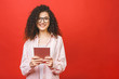 © denis_vermenko - Beautiful curly young girl smiling using tablet isolated over red background. Copy space.