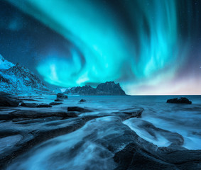 Wall Mural - northern lights above snowy mountains and sandy beach with stones. aurora borealis in lofoten island