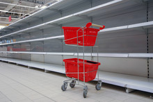 Shopping Trolley With Empty Baskets Against Empty Shelves In Grocery Store