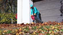 Female Worker Blowing Leaves From Garage Entrance. Girl Using Leaf Blower