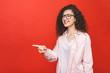 © denis_vermenko - Photo of happy young student woman standing isolated over red wall background. Looking camera showing copyspace pointing.