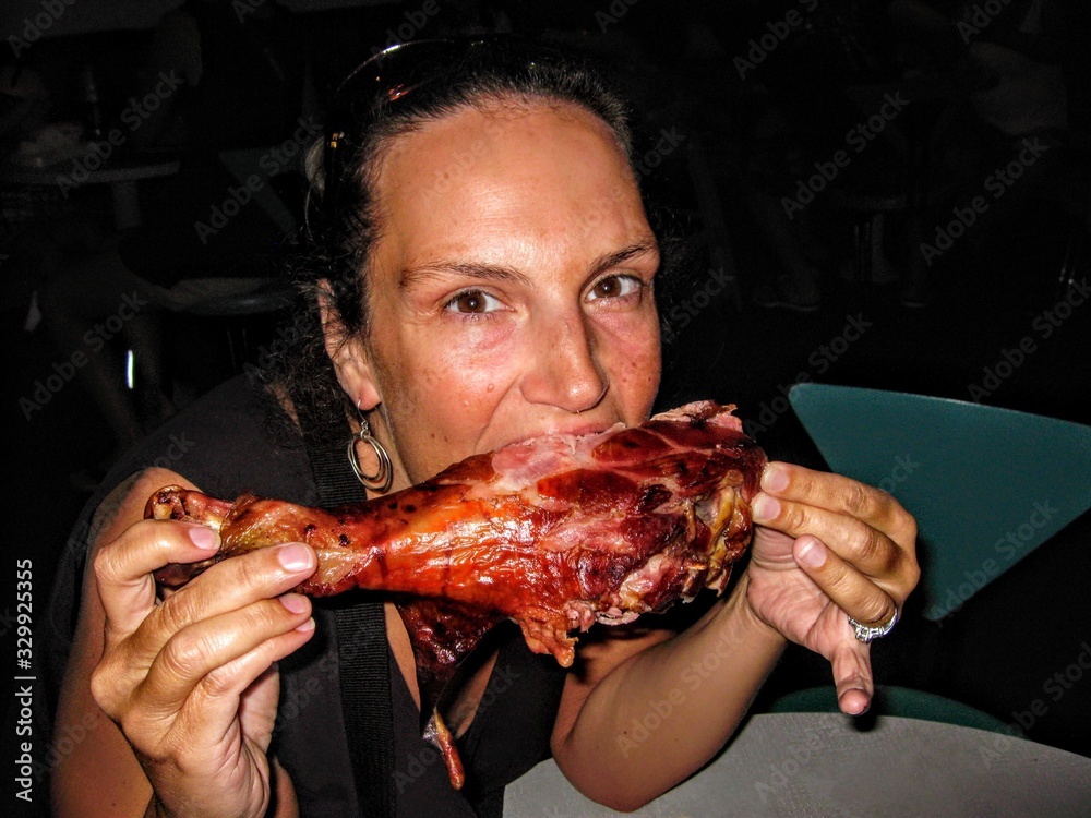 Portrait Of Woman Eating Turkey Leg At Restaurant - obrazy, fototapety, plakaty 