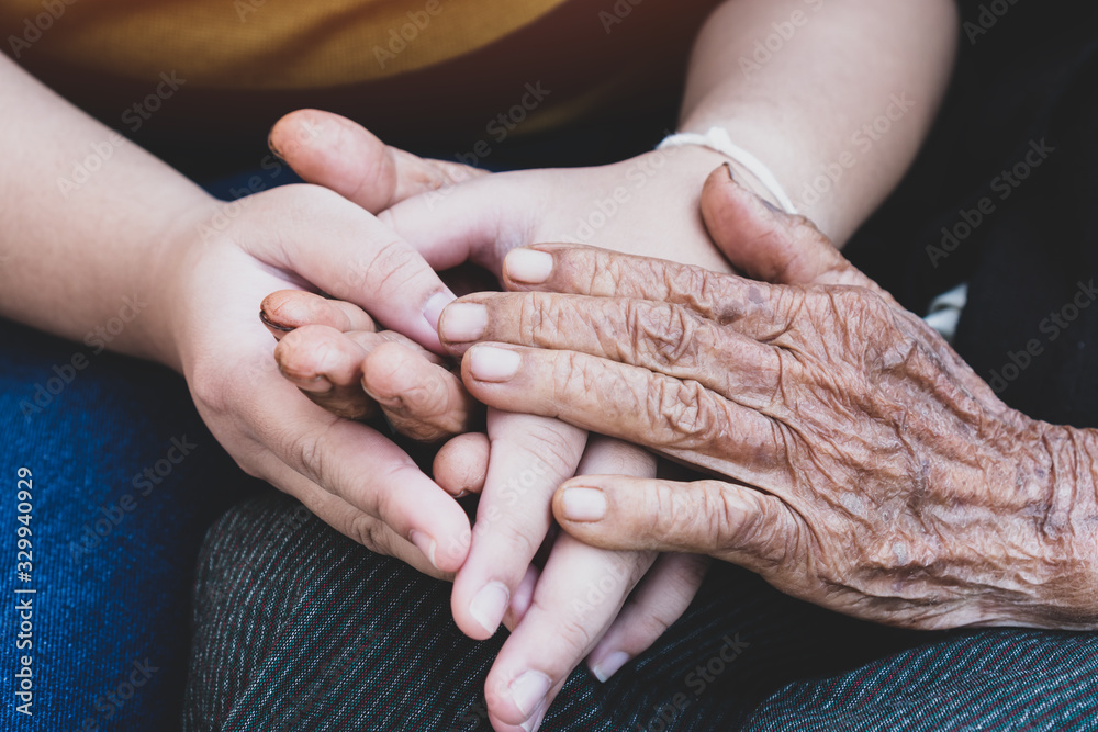 Young grandchildren's holding older grandmother hands feel with support together, wrinkled skin with feeling take care. World Kindness Day, Adult day center Relationship of Family mother day concept - obrazy, fototapety, plakaty 