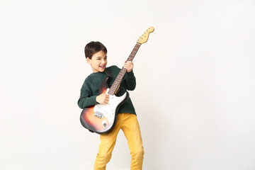 Little boy playing guitar on light background