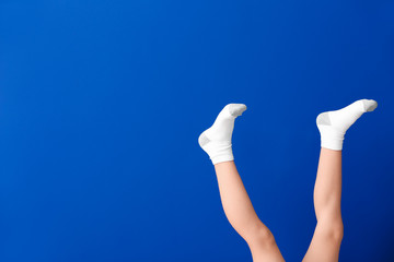 legs of little girl in socks on color background