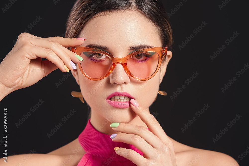 Young woman with beautiful manicure on dark background