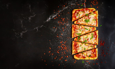 Hawaiian pizza on black stone background, top view.