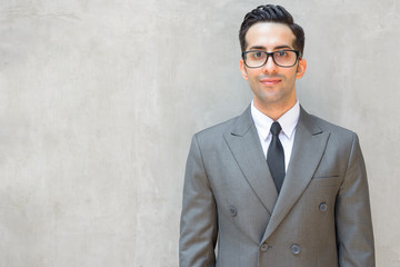 Wall Mural - Young handsome Persian businessman wearing eyeglasses against concrete wall outdoors