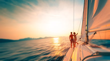 Young Couple Enjoys Sailing In The Tropical Sea At Sunset On Their Yacht. Motion Blurred Image
