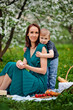 © Elena  - Happy family at a mother 's day picnic. Mom and baby son eat fruit outdoors in a spring blooming or summer Park.