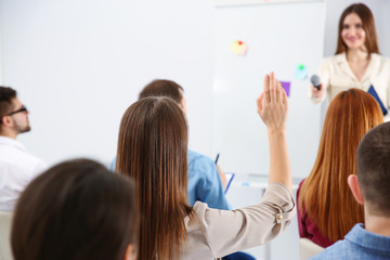 Wall Mural - Young woman raising hand to ask question at business training indoors