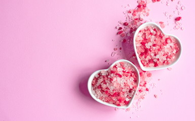 himalayan pink salt on pink paper background in a heart shape saucer