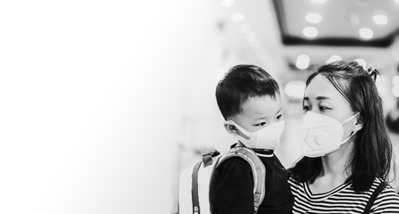 Wall Mural - Coronavirus or Covid-19 concept.Little chinese boy and chinese mother wearing mask for protect pm2.5 in airport terminal.Covid-19 coronavirus and epidemic virus symptoms.black and white.copy space.