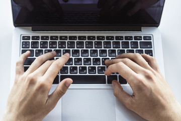 Businessman typing on laptop keyboard in sunny office, business and technology concept. Close up