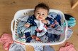 © Lisa Tichané - Overhead view of baby sitting in laundry basket looking up