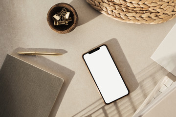 Wall Mural - Blank screen smart phone, stationery on beige background. Flat lay, top view. Styled home office desk workspace. Business, work template.