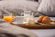 Breakfast in bed with  orange fruits and pastries on a tray
