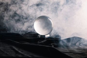 crystal ball on textile with smoke on dark background