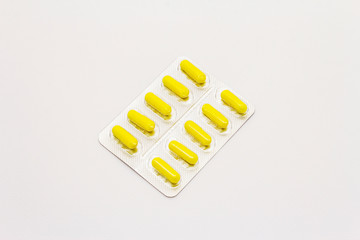 Pharmaceutical tablets, yellow capsules in blister pack isolated on white background