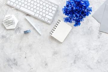 Poster - Summer vibes at work. Office desk with cornflowers bouquet on grey background top-down frame copy space