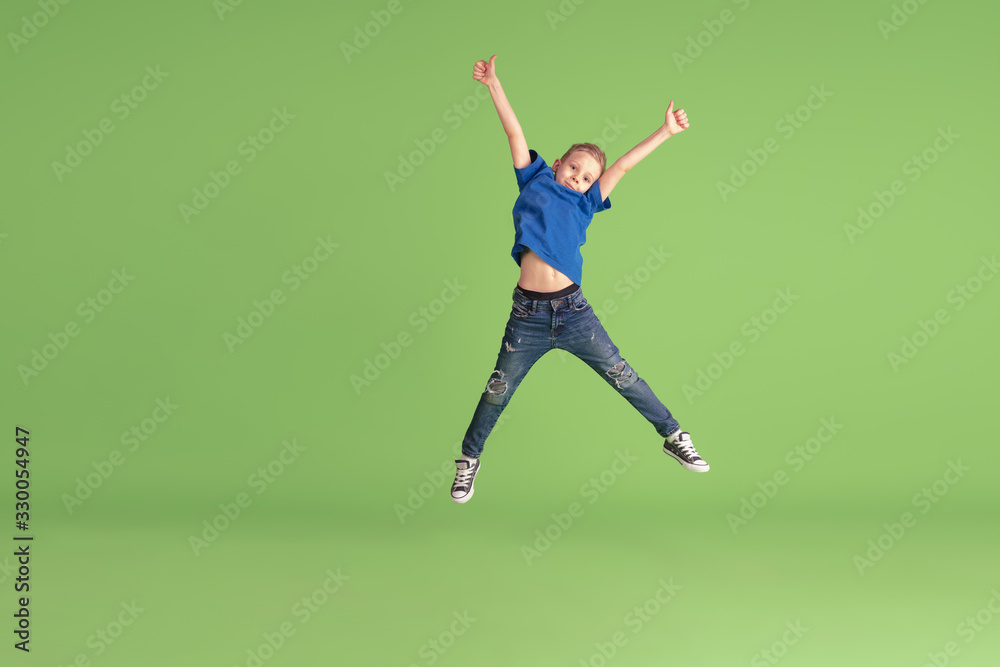 Jumping high. Happy boy playing and having fun on green studio ...
