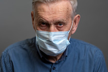 Portrait Of An Old Man In A Medical Protective Mask. A Concept Of The Danger Of Coronavirus For The Elderly