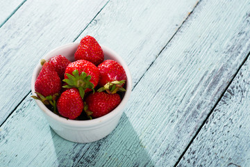 Sticker - pile of strawberry fruits in porcelain bowl on old blue wooden table