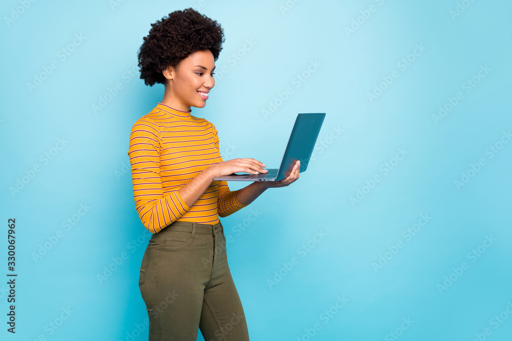 Profile photo of pretty dark skin wavy lady hold notebook hands reading broker service website want to buy apartments wear yellow striped jumper isolated blue color background - obrazy, fototapety, plakaty 