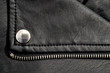 Fragments of a black artificial leather jacket with rivets and zippers. Background for clothes and metal accessories.