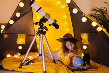 Wall Mural - small girl using earth globe at home living room in a tent.
