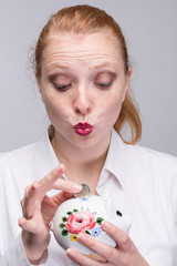 Wall Mural - young woman puts a coin into a piggy bank