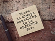Motivational and inspirational wording. There Is Always Something To Be Grateful For written on an adhesive note. Vintage styled background.