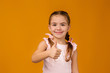 © producer - happy beautiful little child girl in dress showing thumbs up on yellow background.