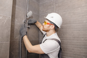 Plumber installing shower stall, work in bathroom