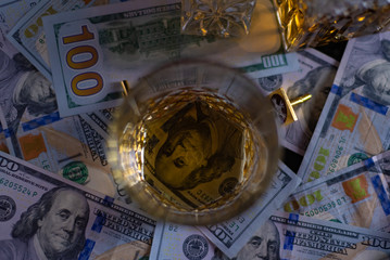 Money on the table. Hundred dollar bill shines through the bottom of a glass of whiskey