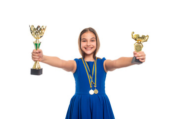 A happy and successful young teenager girl  holds  two gilded cups in her hands, awards - medals hang on her neck.