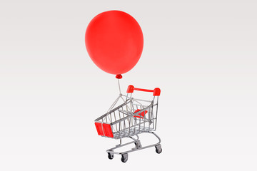 Empty shopping cart and red balloon floating on white background