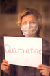 A portrait of woman indoor behind the window holding paper with word Quarantine. People, medicine, healthcare concept. Coronavirus epidemic