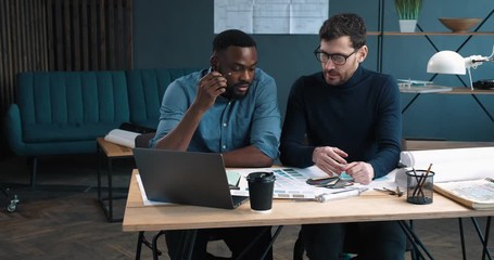 Two creative Designers sitting in modern Studio-Office, choosing Colors.Two mixed Rase People working in Team. Elegant clothed Architect talking in Office with Creative Designer, having Business Meet.