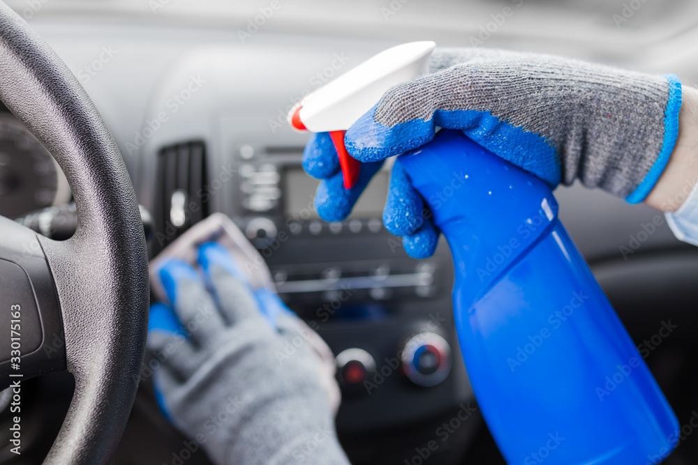 Close up of man hands using microfiber cloth and spray bottle while cleaning car interior. - obrazy, fototapety, plakaty 