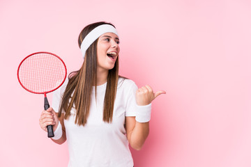 Sticker - Young caucasian woman playing badminton isolated points with thumb finger away, laughing and carefree.