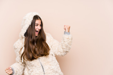 Wall Mural - Young caucasian woman posing isolated raising fist after a victory, winner concept.